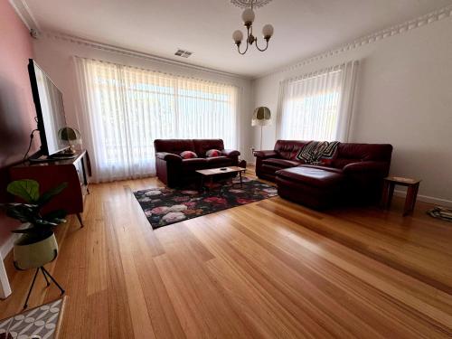 a living room with a couch and a table at Happy Stays - Retro Haven in Shepparton