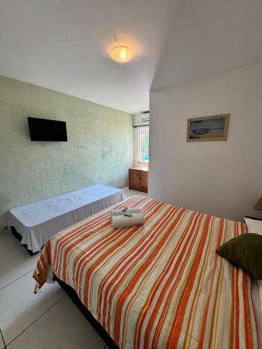a bedroom with two beds and a tv on the wall at Pousada Santa Monica in Saquarema
