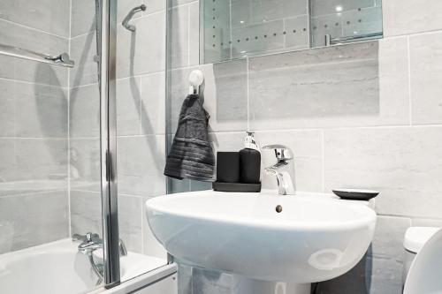 ハウンズローにあるSomerville Apartment London Heathrowの洗面台とシャワー付きの白いバスルーム