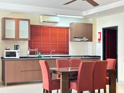 a kitchen with a wooden table and red chairs at Palm Beach Hotel Dili in Dili