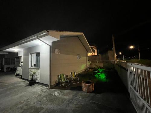 una casa con sillas y una valla por la noche en Hostel Maravilha, en Palhoça