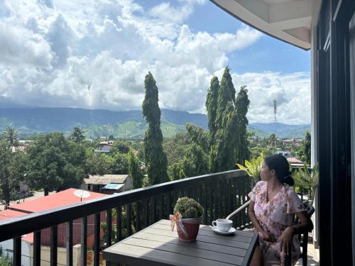 a girl sitting at a table on a balcony at Palm Beach Hotel Dili in Dili