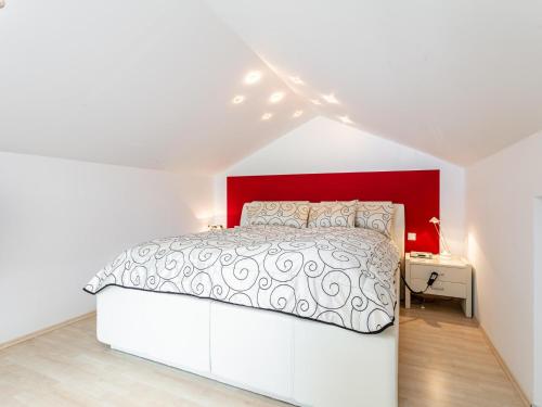 a white bedroom with a large bed with a red headboard at Ferienidyll Kufstein in Kufstein