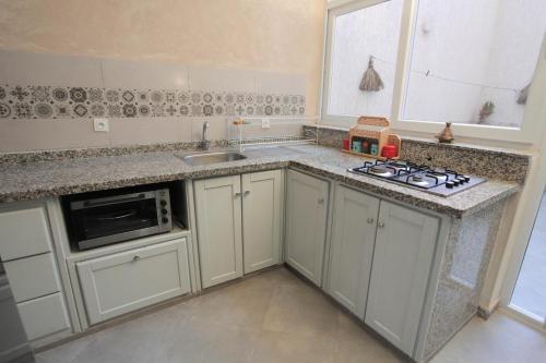 a kitchen with white cabinets and a sink and a stove at Dar Simane Aftas in Mirleft