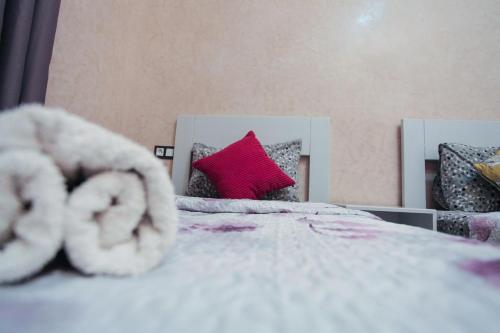 a bedroom with a white bed with a red pillow at Dar Simane Aftas in Mirleft