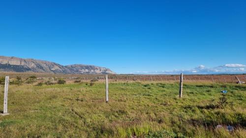 a fence in a field with mountains in the background at Cabaña Ecológica El Puesto in Puerto Natales