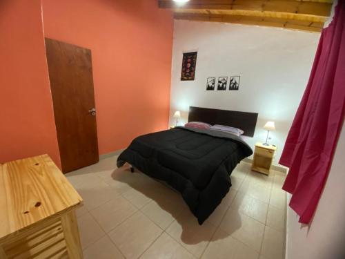 a bedroom with a black bed and orange walls at Casitas Del Champaqui in Villa Yacanto