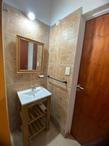 a bathroom with a sink and a wooden door at Casitas Del Champaqui in Villa Yacanto