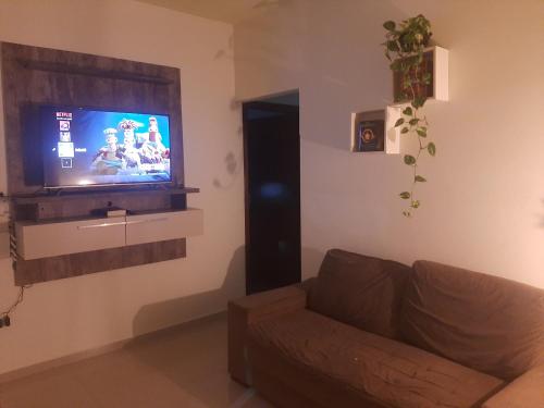 a living room with a couch and a flat screen tv at Chácara agradável com piscina in Brotas