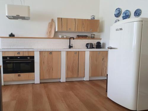 a kitchen with a white refrigerator and wooden cabinets at JaNa in Kaatsheuvel