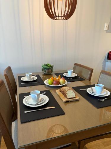 a table with plates and bowls of fruit on it at Aconchego Serra Class 205 Piscina, espaço kids, academia, sauna in Canela