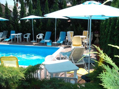 a group of chairs and umbrellas next to a pool at Apart Hévízi Ház in Hévíz