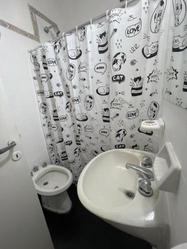 a bathroom with a sink and a toilet and a shower curtain at Casa a 1 cuadra del Río San Antonio in San Antonio de Arredondo