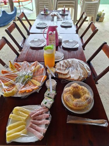 un lungo tavolo in legno con cibo e bevande sopra di Rancho Ohana a Peruíbe