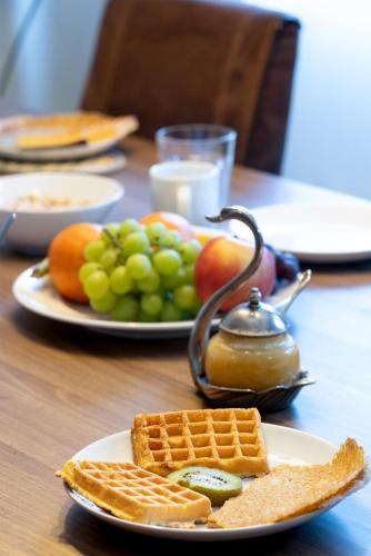 a table topped with plates of food with waffles and fruit at Séjour lodge Namur in Namur