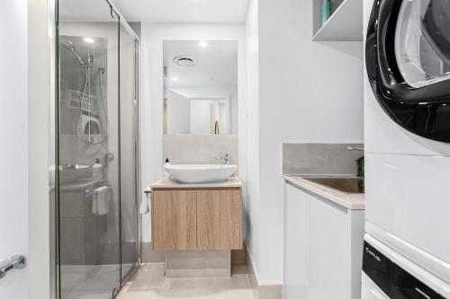 a white bathroom with a sink and a shower at Bokarina Beach Apartments, an Ascend Collection Hotel in Bokarina