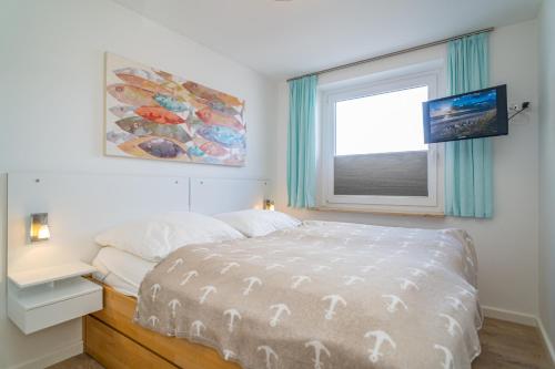 a white bedroom with a bed and a window at Apartmenthaus Dünenburg Dünenburg App 31 in Westerland (Sylt)