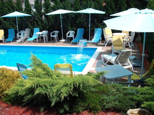 a pool with chairs and tables and umbrellas at Apart Hévízi Ház in Hévíz