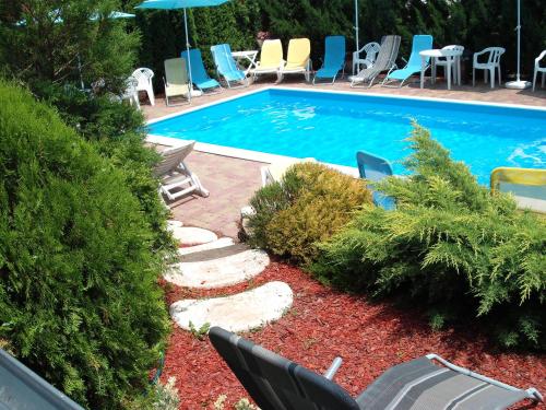 a swimming pool in a yard with chairs around it at Apart Hévízi Ház in Hévíz