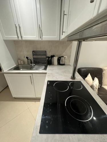 une cuisine avec des armoires blanches et un comptoir noir dans l'établissement Appartement cozy 2 pièce, à Neuilly-Plaisance