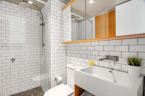 a white bathroom with a sink and a toilet at Gorgeous City Views 64th Floor 3BR APT with Pool & Gym in Melbourne