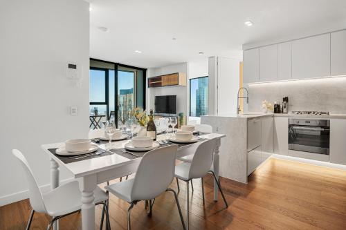 a kitchen and dining room with a white table and chairs at Gorgeous City Views 64th Floor 3BR APT with Pool & Gym in Melbourne