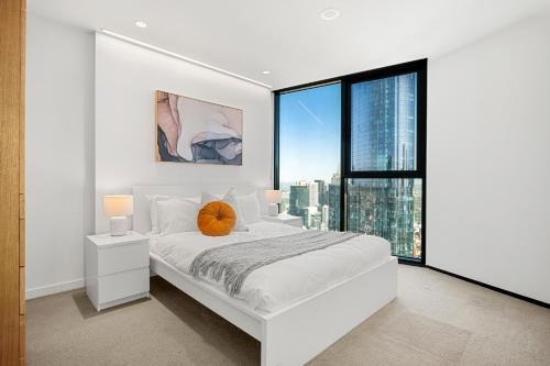 a bedroom with a white bed and a large window at Gorgeous City Views 64th Floor 3BR APT with Pool & Gym in Melbourne