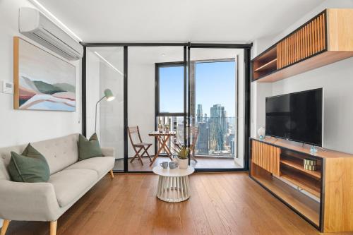 a living room with a couch and a tv at Gorgeous City Views 64th Floor 3BR APT with Pool & Gym in Melbourne