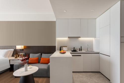 a kitchen and living room with a couch and a table at Ascott Fengyishan Shenzhen in Shenzhen