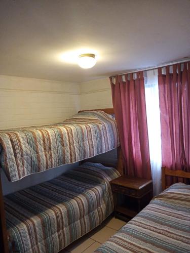 two beds in a small room with red curtains at Casa Centrica Pucón in Pucón