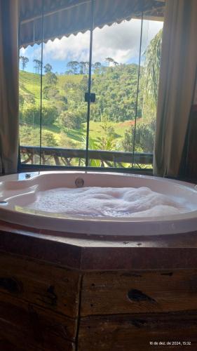 a bath tub with a view of a window at Chalés Fenix in Santo Antônio do Pinhal