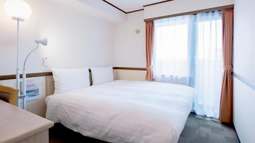 a bedroom with a white bed and a window at Toyoko Inn Hokkaido Sapporo-eki Nishi-guchi Hokudai Mae in Sapporo