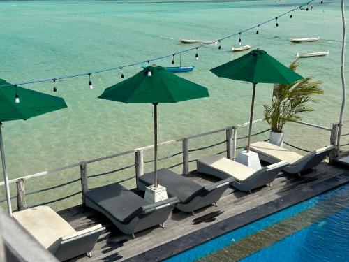 una piscina con sillas y sombrillas junto al agua en Rumah Marta Ceningan Island, en Nusa Lembongan
