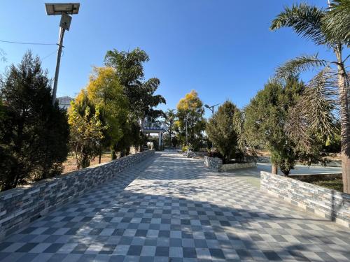 a cobblestone road in a park with trees at JSB Farms in Jhājra