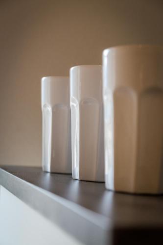 four white cups sitting on top of a shelf at Appartements Lilly Rose in Zell am Ziller