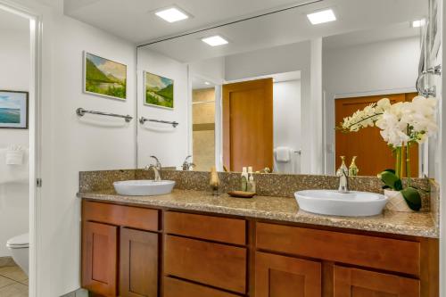 a bathroom with two sinks and a large mirror at Poipu Sands 437: 2BR Ocean View Condo w/ A/C, pool in Koloa