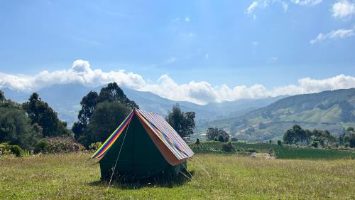 a tent in a field with mountains in the background at CorpoAgro HJC in Sonsón