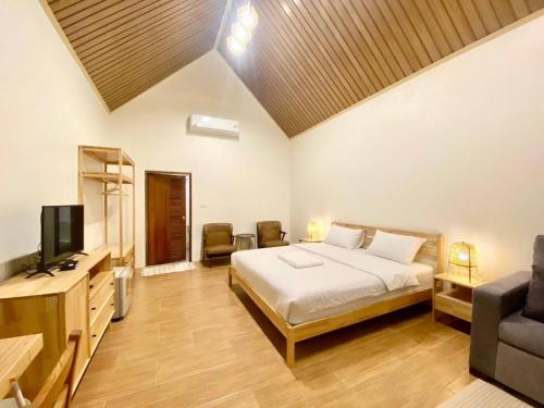 a bedroom with a bed and a tv and a couch at Baan Pong Tara in Suan Phung