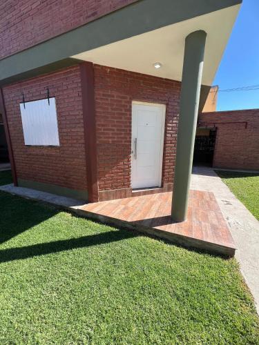 a brick building with a white door and grass at Complejo Las Hortensias de Fausti in Jesús María