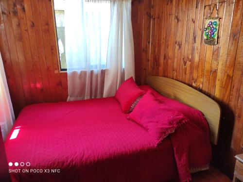 Cabaña el Diuco في كونياريبي: غرفة نوم مع سرير وملاءات حمراء ونافذة