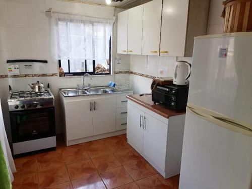 Cabaña el Diuco في كونياريبي: مطبخ بخزائن بيضاء ومغسلة وثلاجة