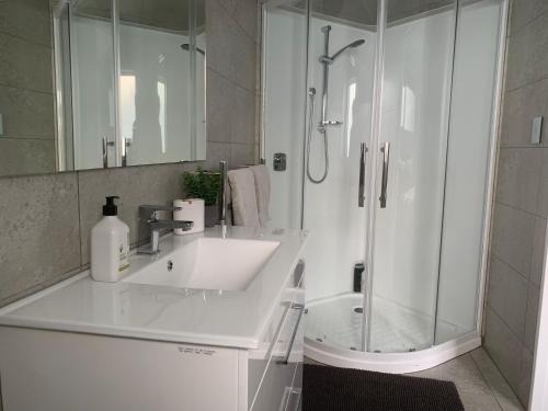 a white bathroom with a sink and a shower at Mason lane Apartment in Whangarei