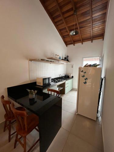 Una cocina con encimera negra y refrigerador. en Casa na praia Silvana, en Caraguatatuba