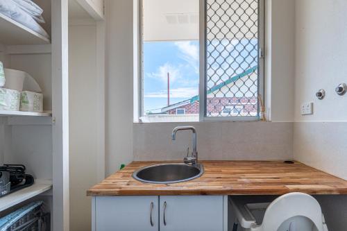 eine kleine Küche mit Spüle und Fenster in der Unterkunft A1 Airport Haven - Quick Access, Comfy & Free Parking in Perth