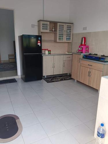 a kitchen with a black refrigerator and a white tile floor at Auni Homestay in Raub