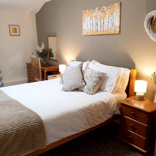 a bedroom with a bed with white sheets and pillows at Apple Blossom Guesthouse in Rempstone