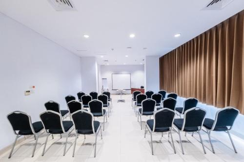 a conference room with black chairs and a podium at Whiz Prime Hotel Balikpapan in Balikpapan