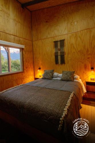 a bedroom with a large bed with a window at Cabañas Leufu in Futaleufu