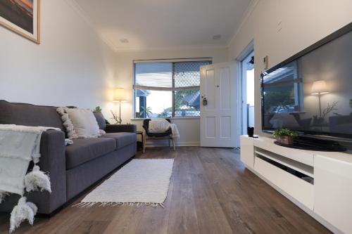 a living room with a couch and a flat screen tv at B1 AirportHaven - Free Parking & Modern Comfort in Perth