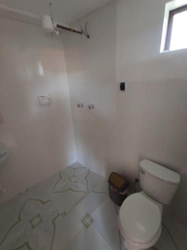a white bathroom with a toilet and a window at Hostal Margarita in Comunidad Challapampa